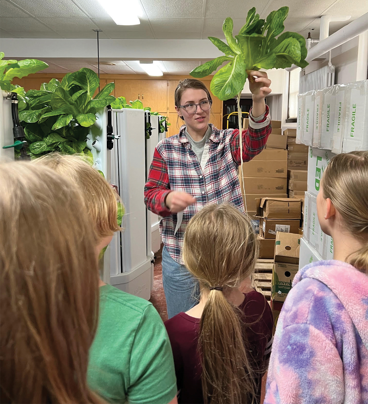 Grow It Forward Urban Farm Manager Nina Loomis shows a local Girl Scout troop roots from the farm’s hydroponically-grown lettuce.