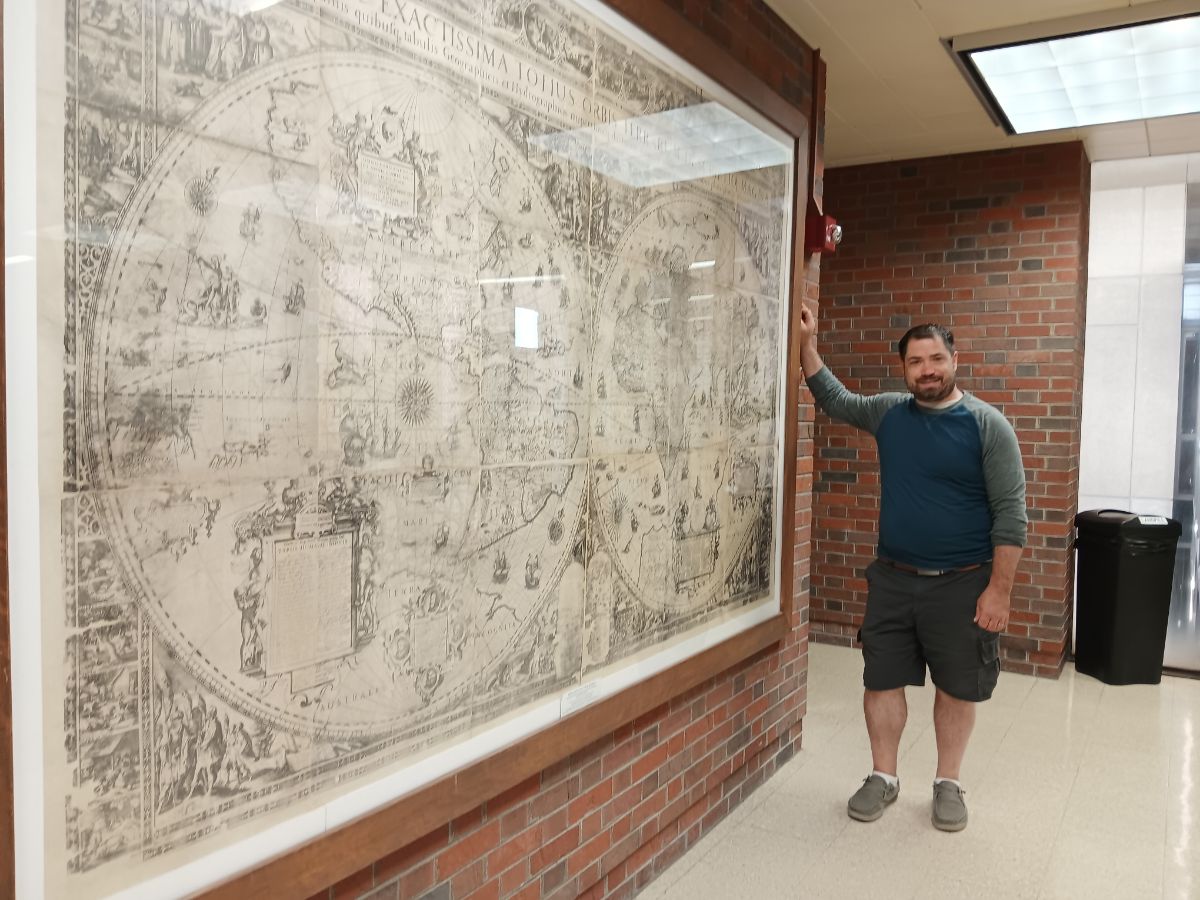 Julius Wagner stands next to a map that is part of the American Geographical Society Library in Milwaukee.