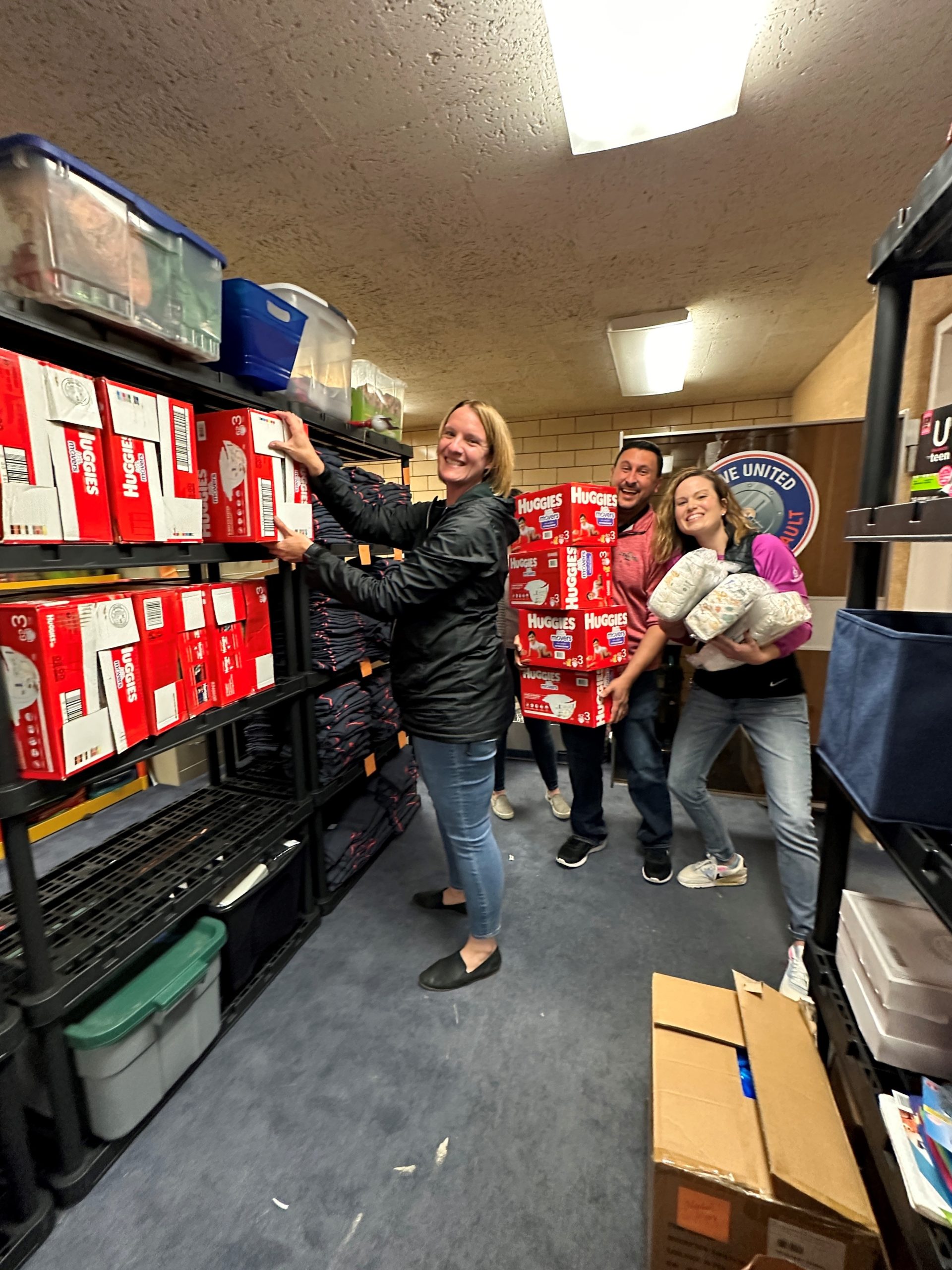 Oshkosh Defense team members place a diapers donation on the shelves at the Live United Community Vault in Oshkosh.