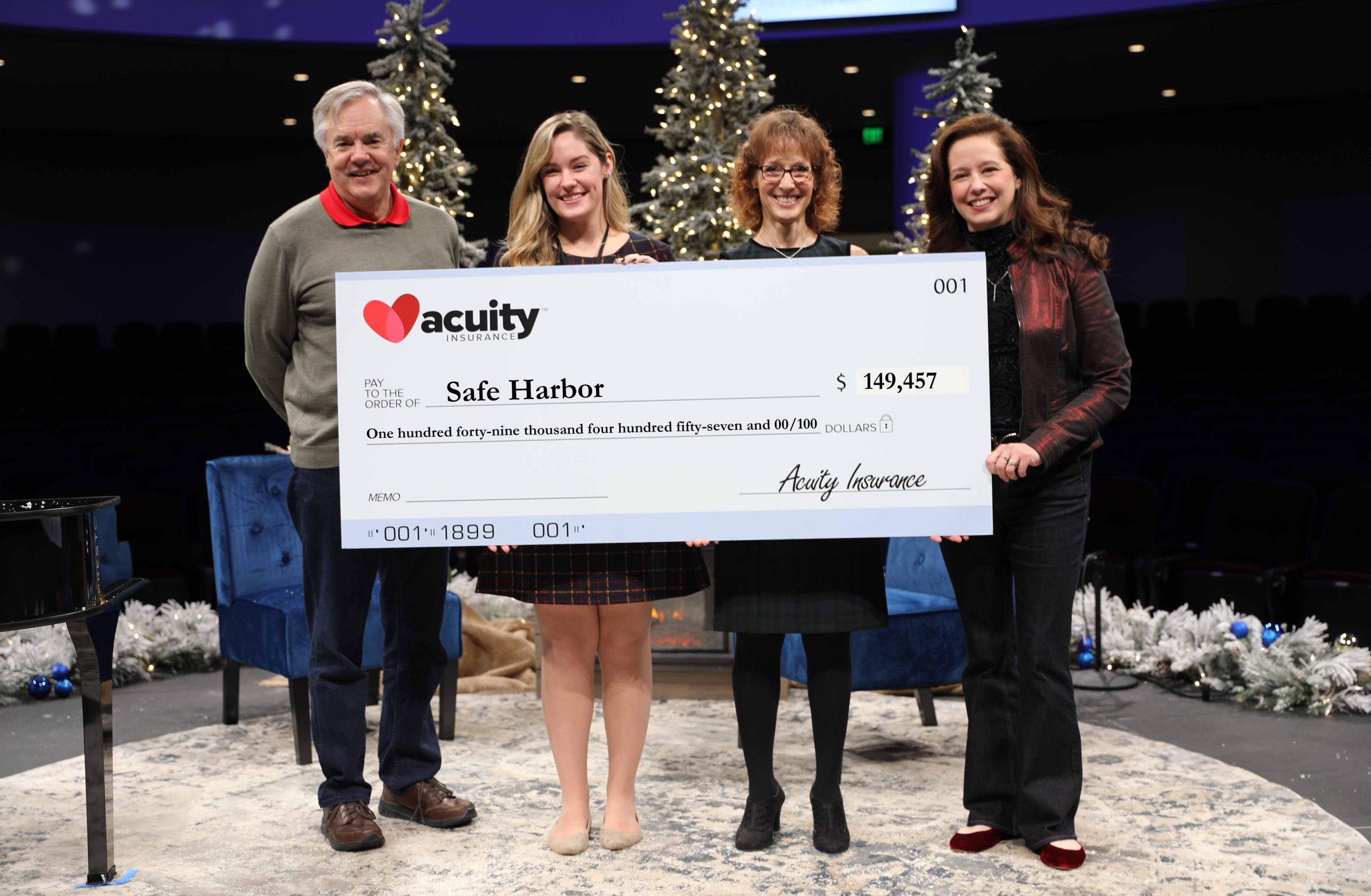 Safe Harbor’s Kelsi Engelhardt accepts a check for nearly $150,000 from AcuityCEO Ben Salzmann, Vice President - Services and Administration Sheri Murphy, and President Melissa Winter.
