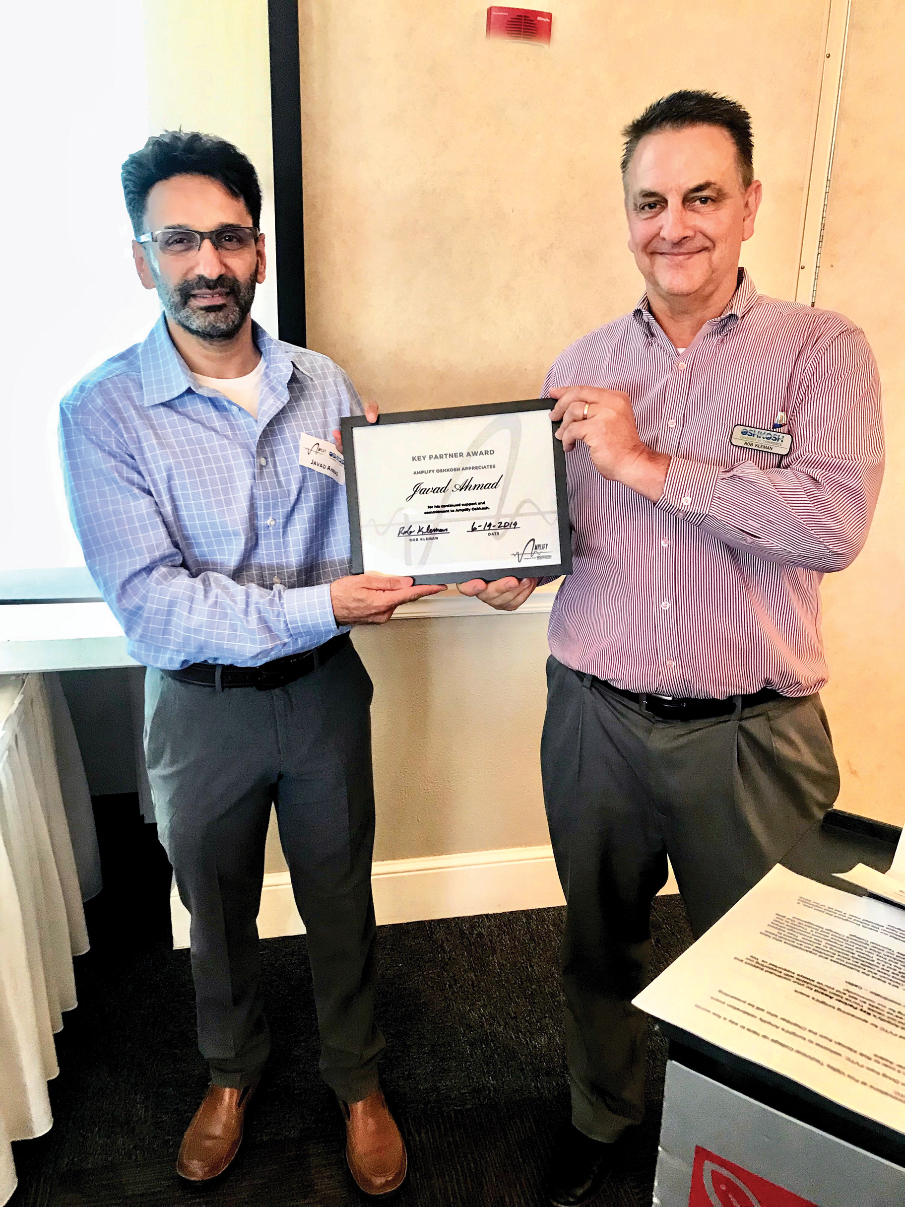 Rob Kleman (R) and the Oshkosh Chamber honored Ahmad (L) with a Key Partner Award for his personal and organizational support of Amplify Oshkosh.