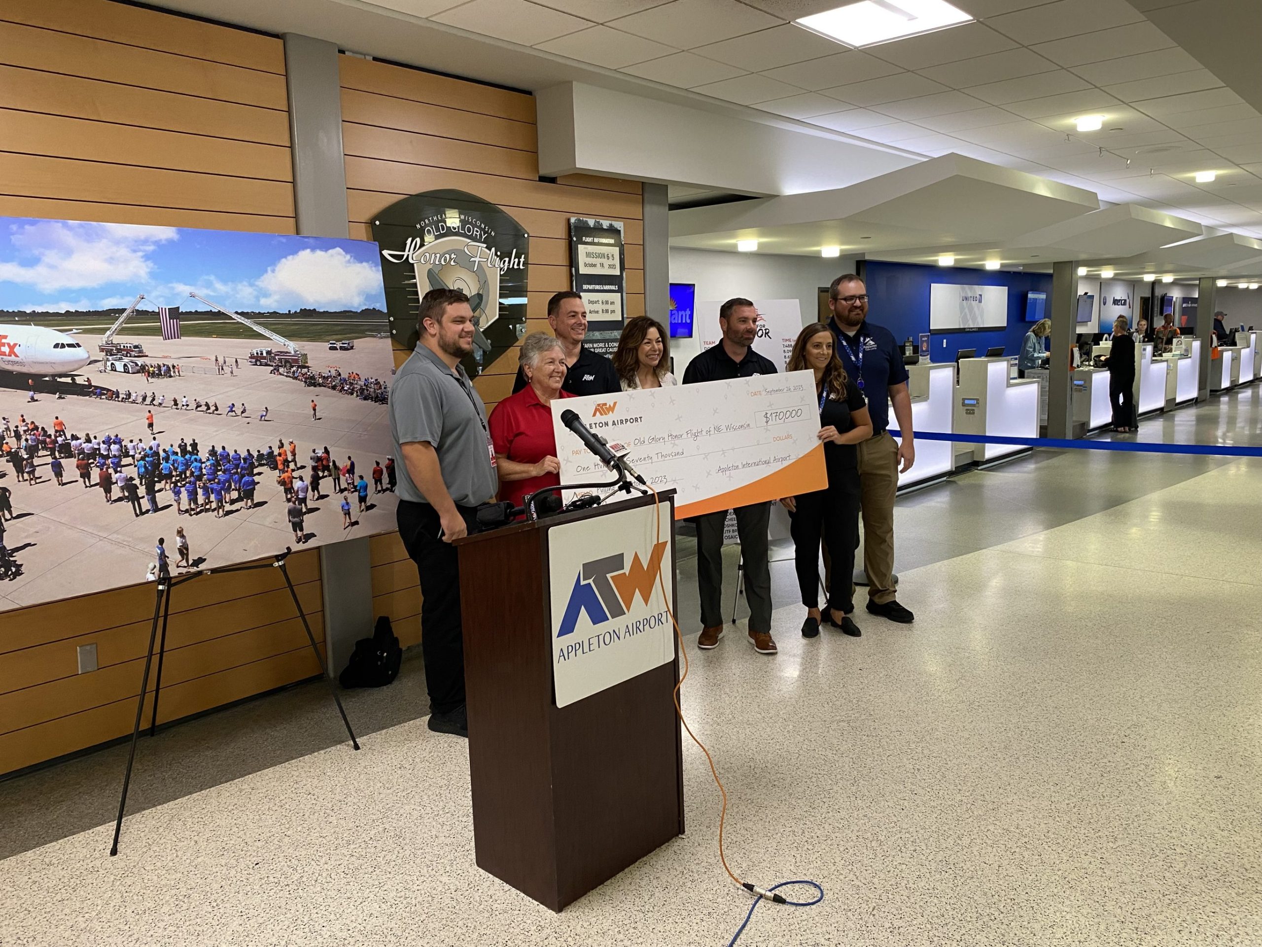 Officials with Appleton International Airport and Old Glory Honor Flight pose with a check containing funds raised through the 2023 