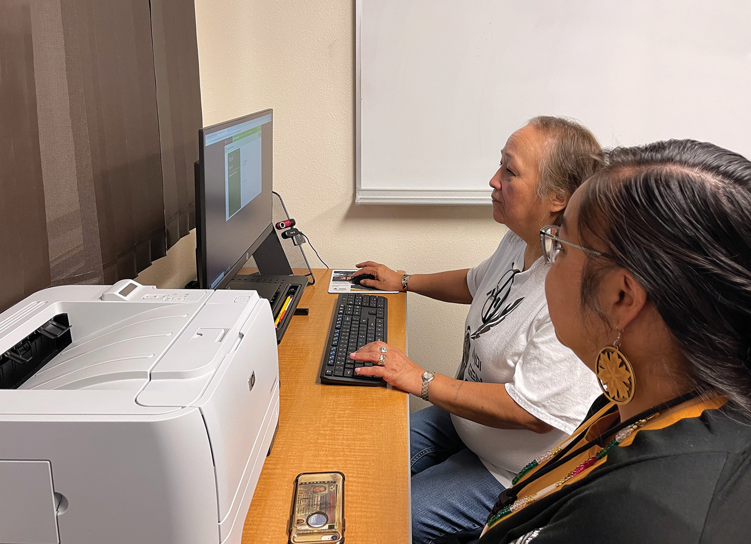 Tasha Komaneikin, College of Menominee Nation employment opportunities coordinator, guides Joyce Pamonicutt, NEW BOOST digital literacy participant, through a training.