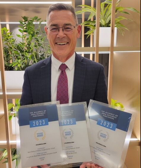 Brian Rasmussen holds three awards from the Association of Area Business Publications.