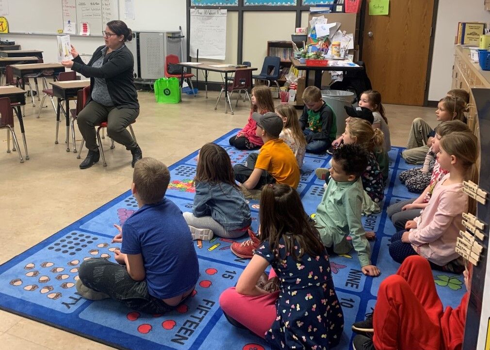 SNBT Mortgage Underwriter and volunteer, Alicia Schneider, reads a book about saving money to children during Teach Children to Save Day.