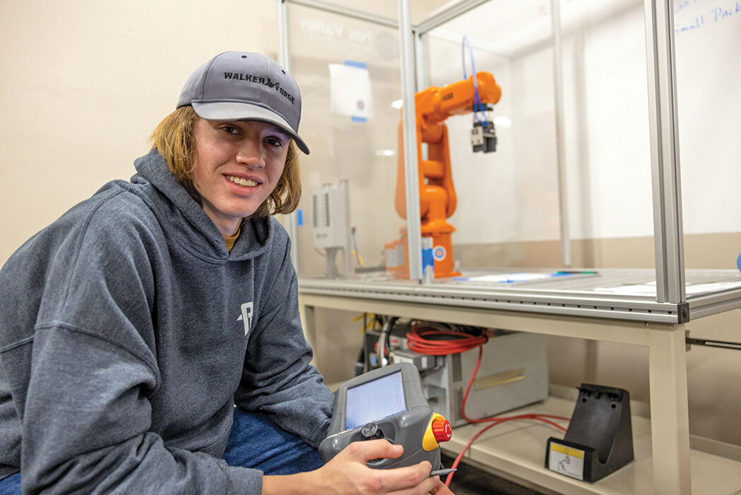 Clintonville Automation & Engineering Academy participant Brody Prill programs an industrial robot to automatically stack objects.