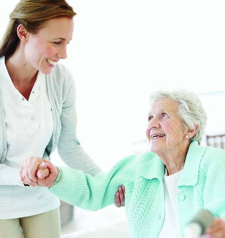 Daughter helps her elderly mother stand up in preparation to use her walker