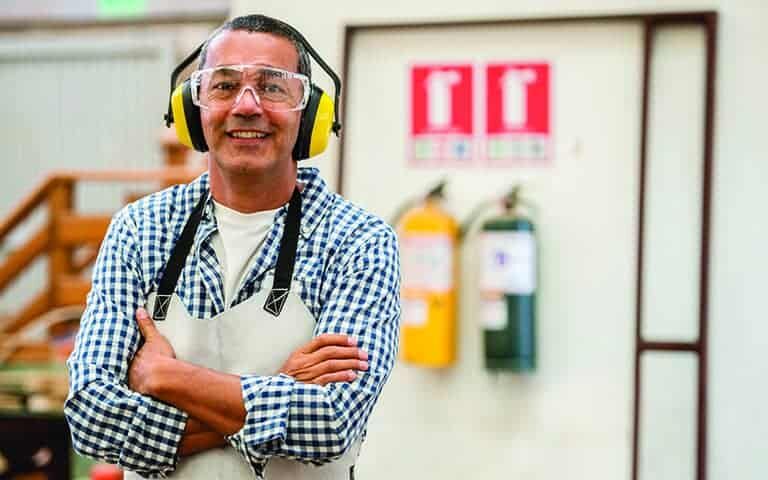 Carpenter wearing protective workwear at the carpentry like glasses, apron and ear protectors
