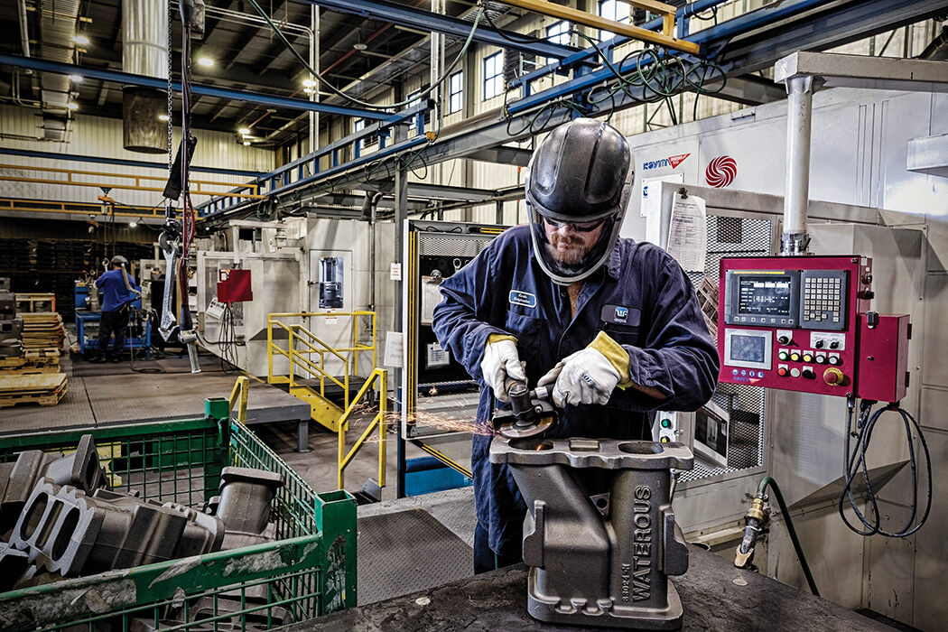 A spin blast operator at Waupaca Foundry inspects and finishes an 85-pound adaptor for municipal application.