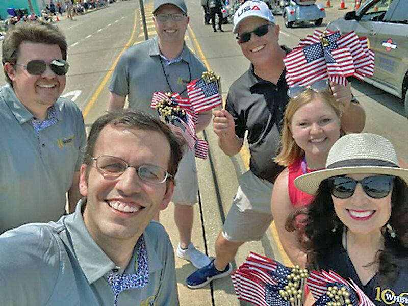 WHBY staff handing out flags prior to June 2025 Appleton Flag Day Parade. (Left to right) Zach Morris, Ben Cominos, Landen Moore, Jonathan Krause, Hope Bowe, Nanci Micke.