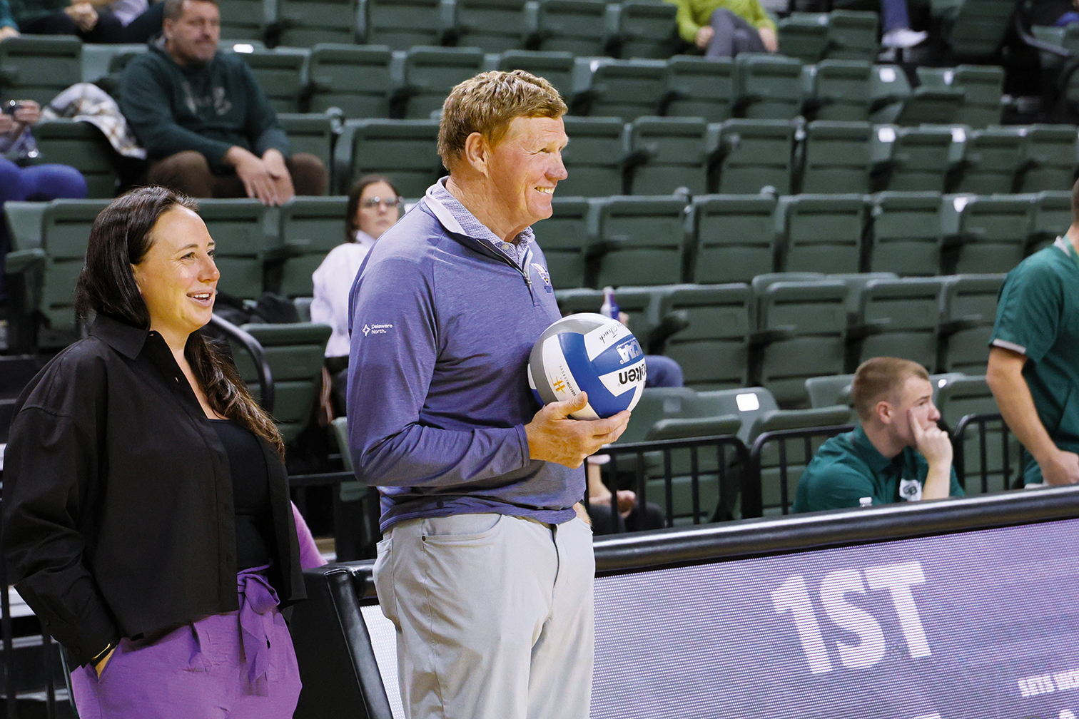 Mark Murphy presents a game ball alongside UWGB Women’s Volleyball Coach Abby Sutherland.
