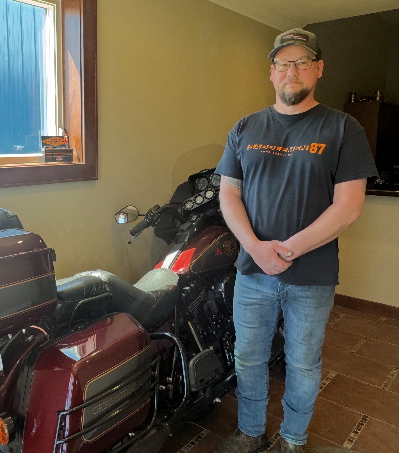 Joe Ruelle stands alongside a Harley-Davidson motorcycle.